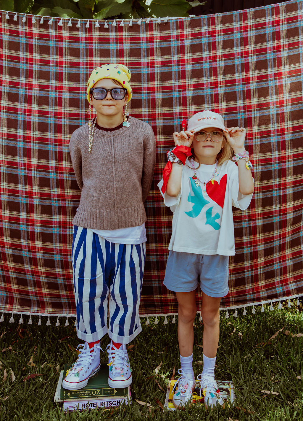 Two children posing in front of a plaid backdrop