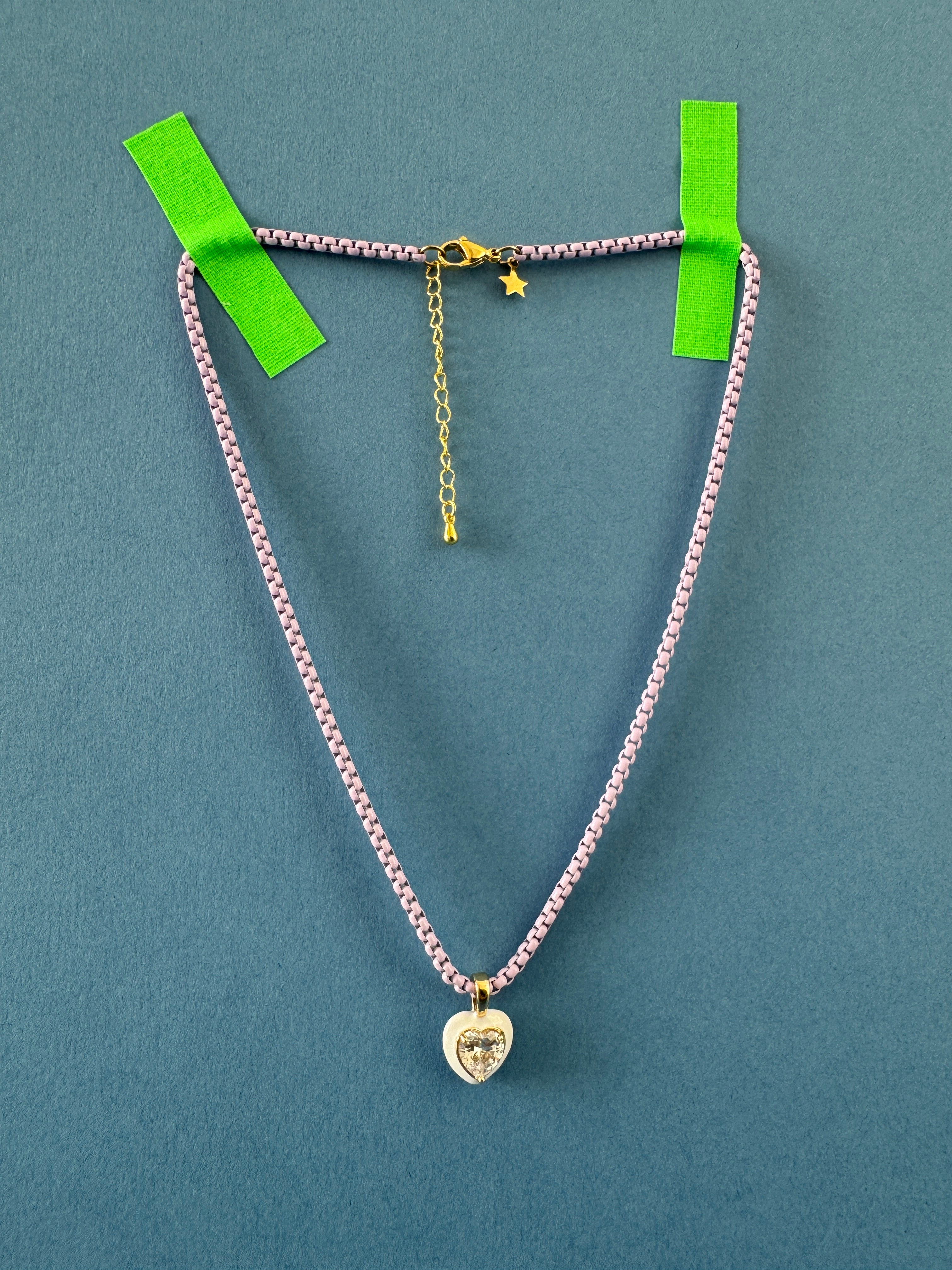 purple chain necklace with heart charm on a blue background