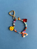 Colorful beaded keychain with heart charm and smiley face on a blue background
