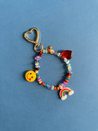 Colorful beaded keychain with heart charm and smiley face on a blue background