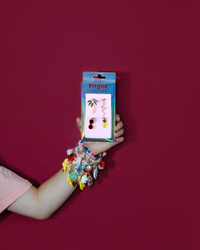 Hand holding a package of colorful charms against a red background