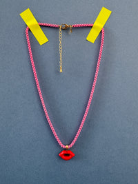 Necklace with pink chain, gold clasp, and red pendant on a gray background