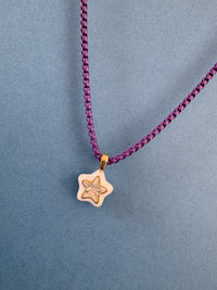 Gold star-shaped pendant on a purple chain