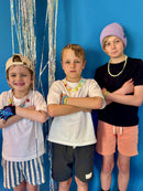 Three children posing against a blue background with decorative streamers.