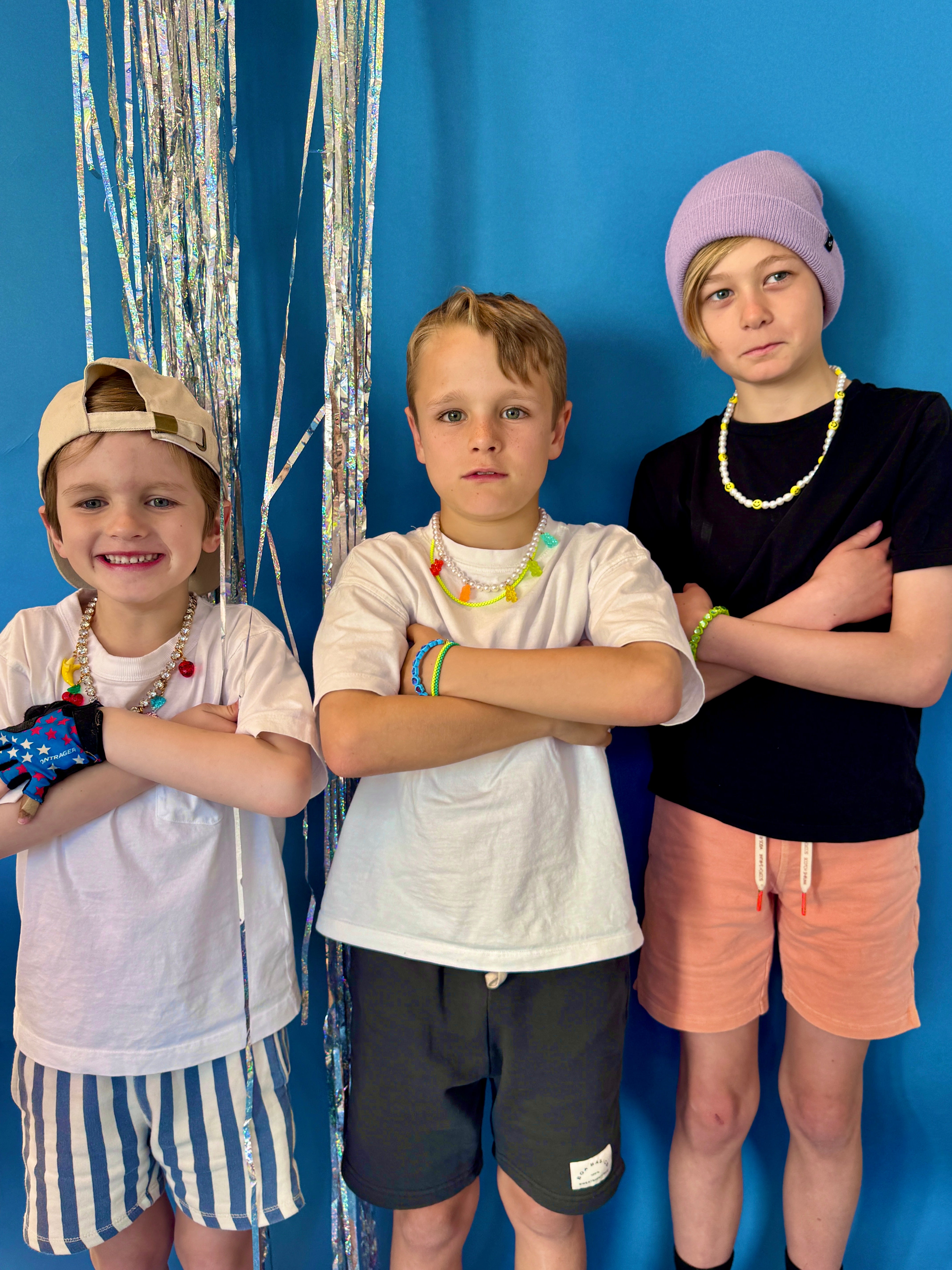 Three children posing against a blue background with decorative streamers.