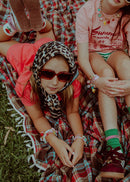 Girls sitting outside on blanket wearing Roger Pearl Power sneaker charms on bracelets.