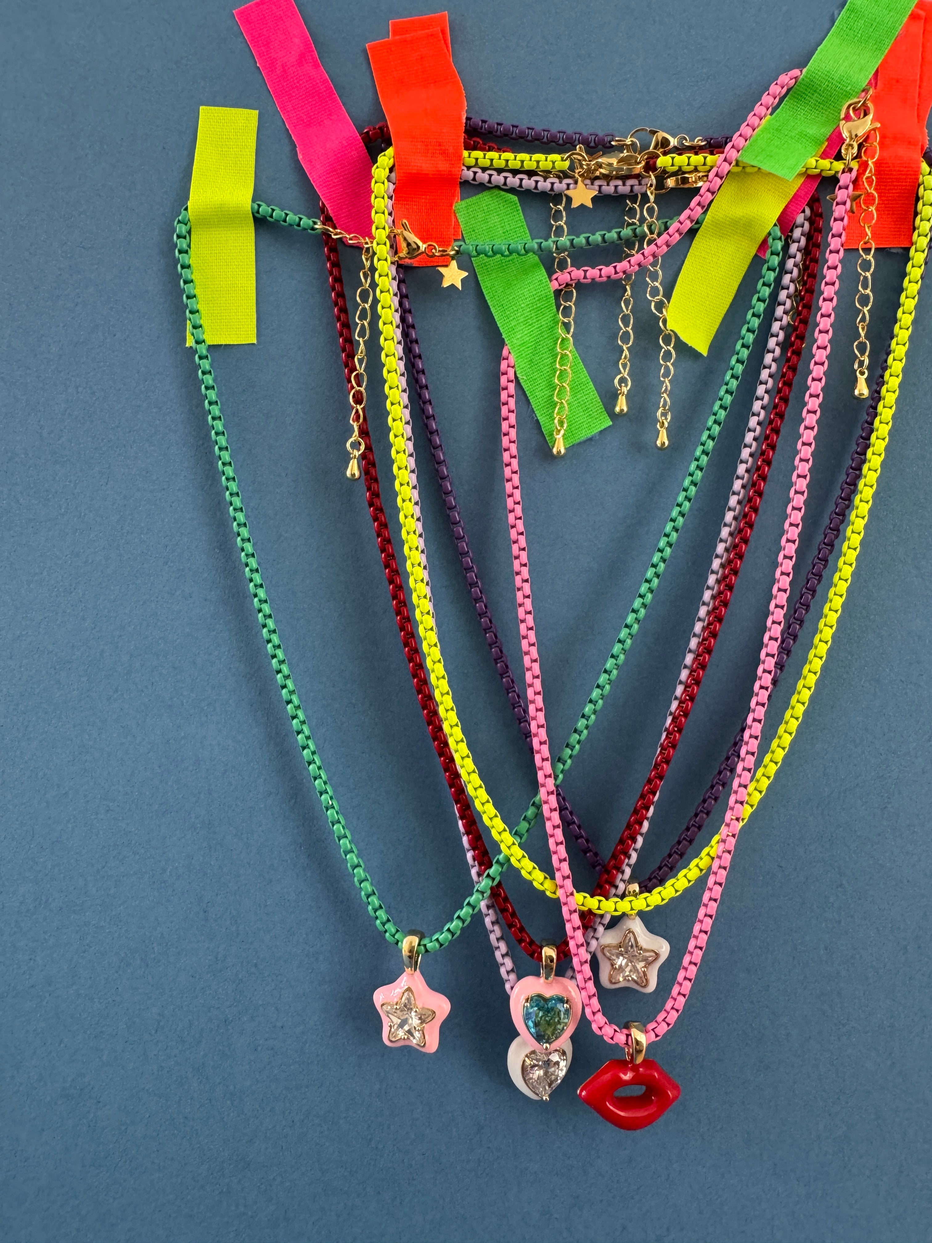 Colorful chain necklaces with star and heart charms on a blue background