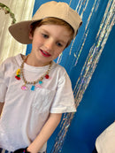 Child wearing a beige cap and colorful necklace against a blue background with decorative elements.