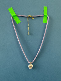 purple chain necklace with heart charm on a blue background