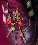 Extra close image of sneaker charms on shoes. Gold bow charm, heart charm, key charm and pearl charm