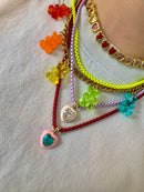Colorful beaded bracelets with heart charms on a light background