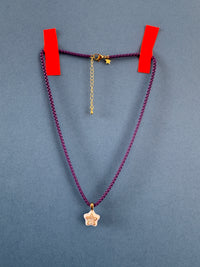Purple cord with gold clasp and chain on a gray background
