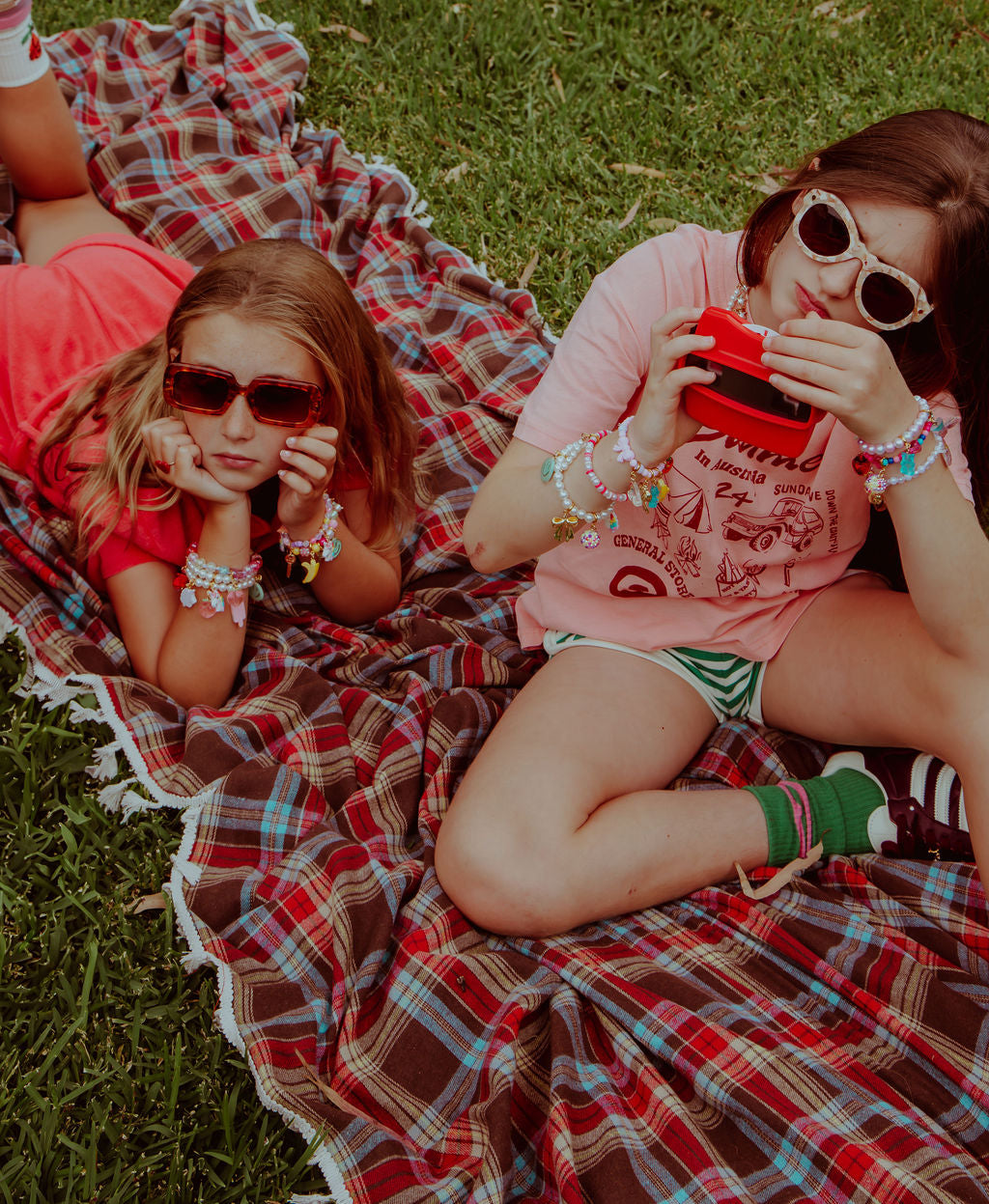 sneaker charms by roger on shoes while girls sit outside on grass.