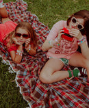 sneaker charms by roger on shoes while girls sit outside on grass.