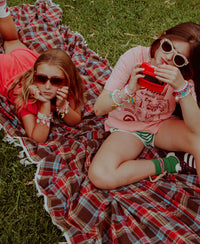sneaker charms by roger on shoes while girls sit outside on grass.