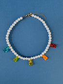 Pearl necklace with colorful gummy bear charms on a blue background