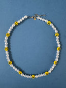 Necklace with white pearls and yellow smiley face beads on a blue background