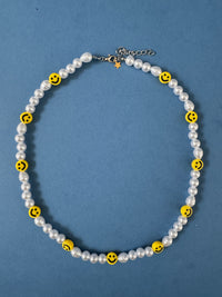 Necklace with white pearls and yellow smiley face beads on a blue background